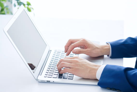 ノートパソコンでウェブサイトの更新作業を行うビジネスパーソンの写真